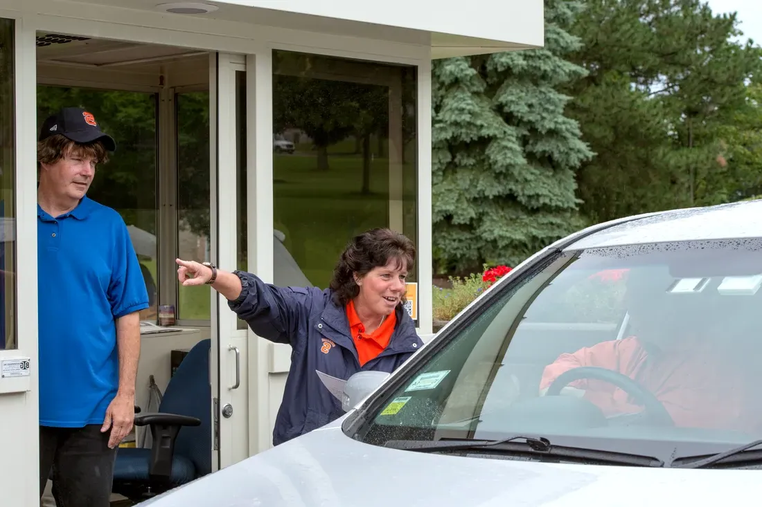 Parking booth attendants direct a car through campus.